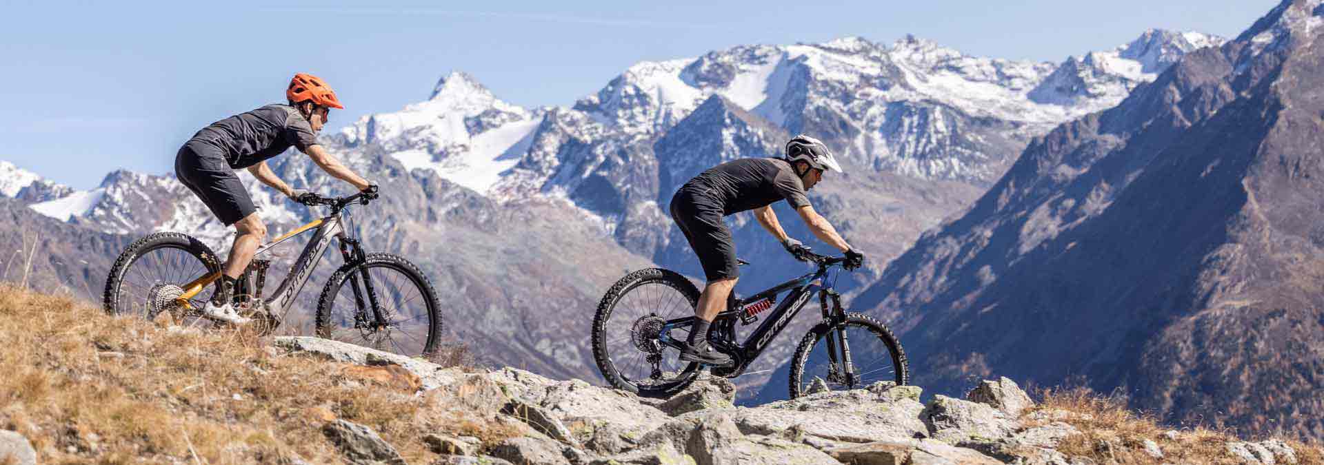 frau-und-mann-auf-e-mountainbikes-fahren-einen-berg-runter