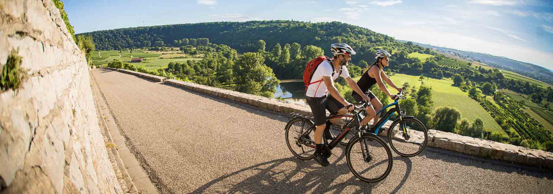paerchen-auf-e-tourenraedern-fahren-auf-asphalt-entlang-eines-waeldchen